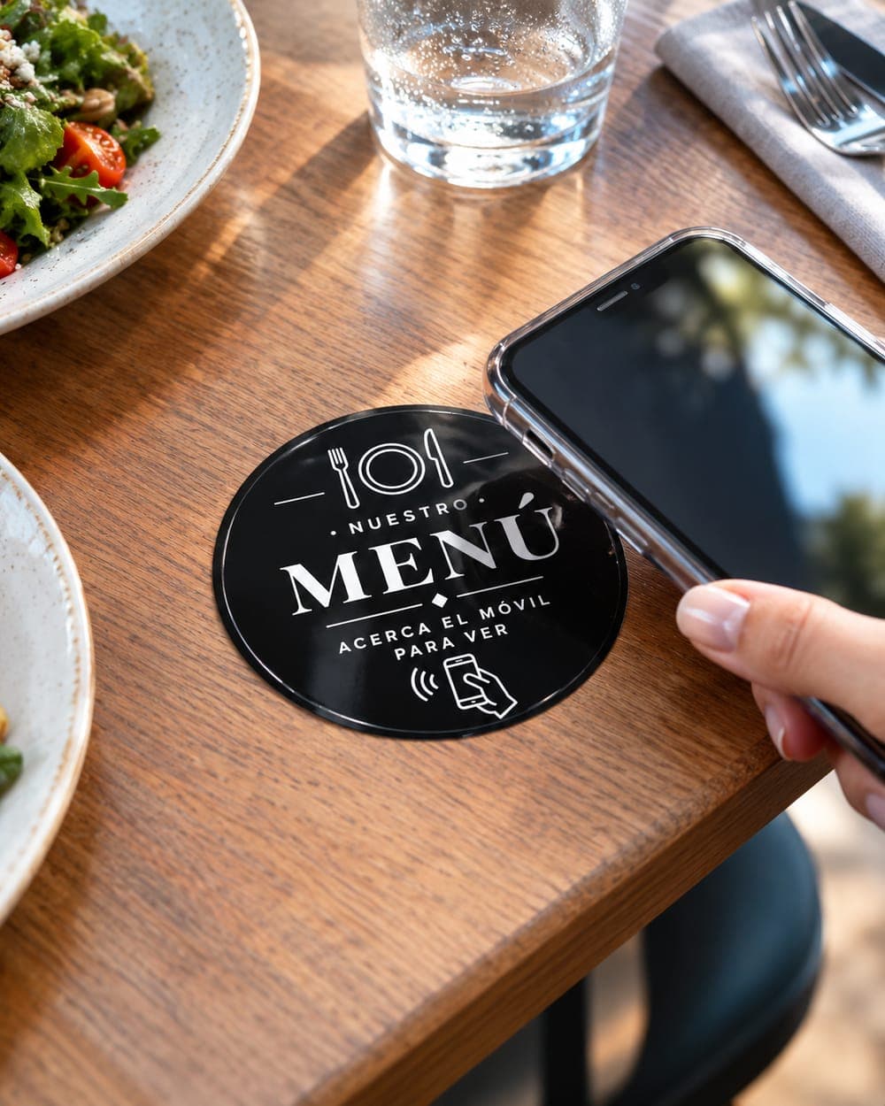 Tarjeta «Nuestro menú» en la mesa de un restaurante con un móvil acercándose